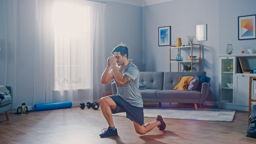 Strong Athletic Fit Man Doing Forward Lunge Exercises at Home in His Spacious and Bright Apartment with Minimalistic Interior.