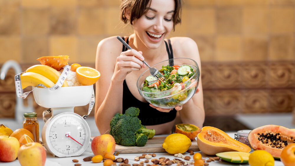 Woman eating lots of  food on the kitchen. Concept of overeating in eating windows during intermittent fasting