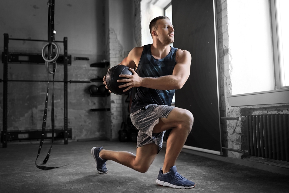 sport, bodybuilding, fitness and people concept - young man exercising with medicine ball in gym