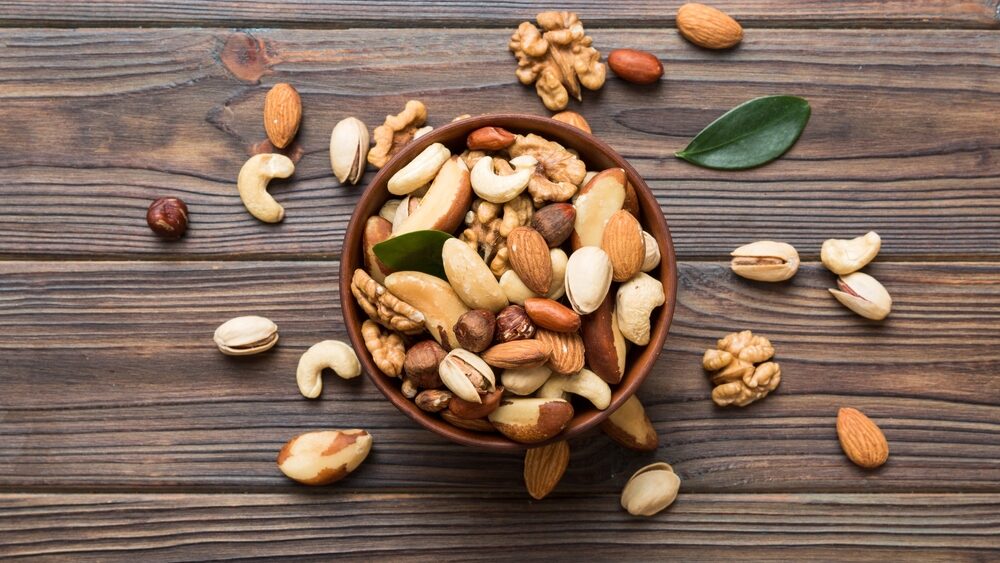 mixed nuts in bowl. Mix of various nuts on colored background. pistachios, cashews, walnuts, hazelnuts, peanuts and brazil nuts.