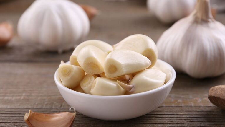 Aromatic garlic cloves and bulbs on wooden table, closeup