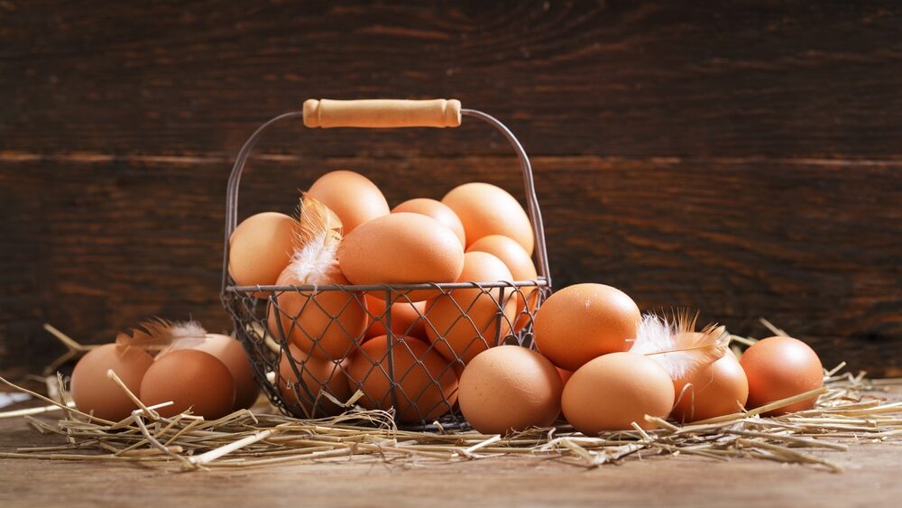 basket of fresh chicken eggs on a wooden background
