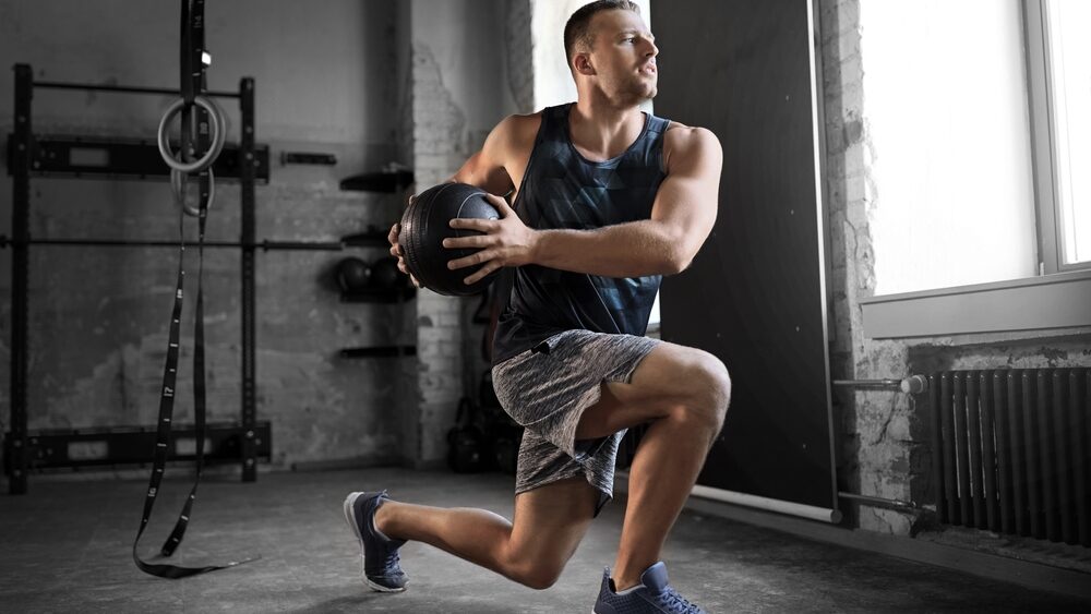 sport, bodybuilding, fitness and people concept - young man exercising with medicine ball in gym