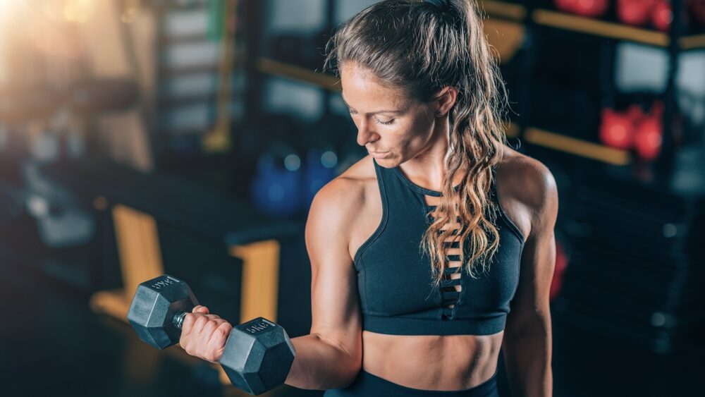 Fit bodybuilder women lifting dumbbell in the gym